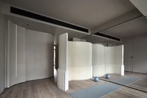 Modern minimalist fitness studio with curved panels featuring a yoga mat and gym equipment.