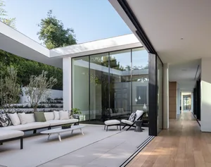 Modern residential patio featuring glass walls and wooden flooring with outdoor seating and greenery.