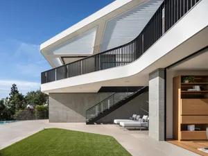 Modern house with a concrete terrace and black railings.