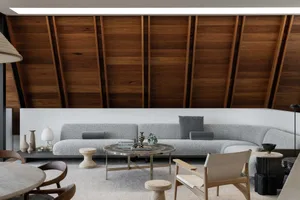 Modern living room with a cozy sofa and round coffee table, featuring a wooden ceiling with exposed beams and a sleek, minima