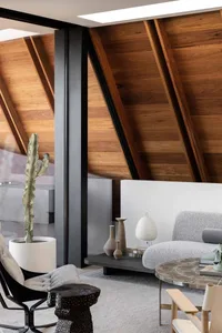 A modern living room featuring wooden walls and beams, with minimalist furniture and decorative items.