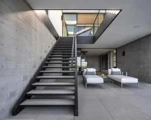 現代極簡室內空間，展示混凝土樓梯搭配黑色鋼製扶手及座位區。