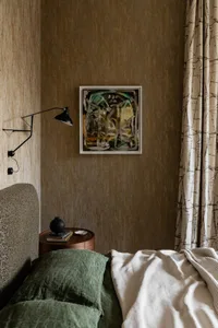 A minimalist bedroom featuring a green bed and wood side table.