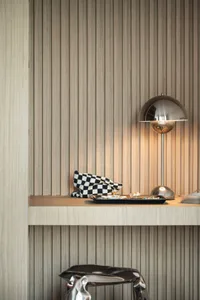 A display of modern accessories on a wooden ledge, featuring a sleek lamp and a checkerboard-patterned pouch.