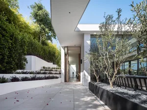 A modern entryway featuring a concrete pavement adorned with small red flowers.