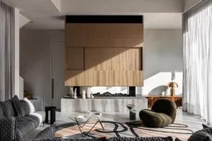 A modern living room featuring concrete walls and a fireplace, with a cozy armchair and a minimalist coffee table.