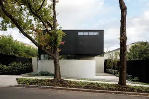 A minimalist modern house exterior featuring a black-glass wall and curved concrete elements.