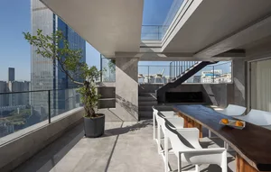 A minimalist balcony design featuring concrete surfaces, white chairs, and a wooden table with oranges.