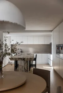 Modern minimalist kitchen featuring marble countertop and white cabinetry.
