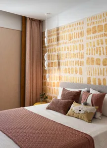 A modern bedroom with a patterned wall, soft furnishings, and a comfortable bed.