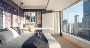 Modern minimalist bedroom with a wooden floor, large window, and city view.