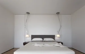 A minimalist white bed with a gray headboard in a modern bedroom setting.
