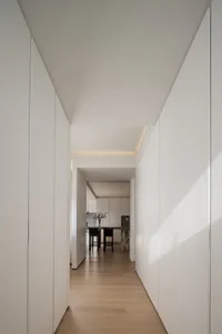 A modern minimalist living room with white walls and a wooden floor.