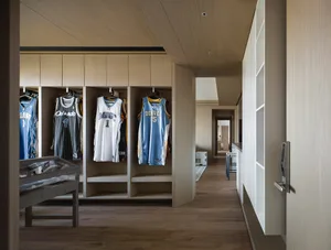 Wooden closet with jerseys hanging on shelves.