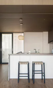 A modern kitchen with a wooden ceiling and floor, featuring a kitchen island with bar stools and a sink.