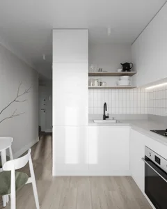 Modern white kitchen with minimalist design, featuring wooden floors and white cabinets.