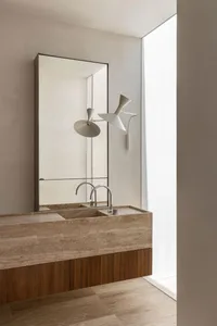 Modern minimalist bathroom featuring a stone vanity with dual faucets and a large mirror.
