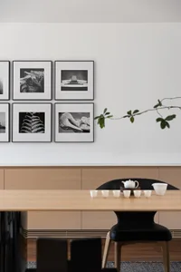A minimalist dining room featuring wooden furniture with a modern black chair and a white tea set.