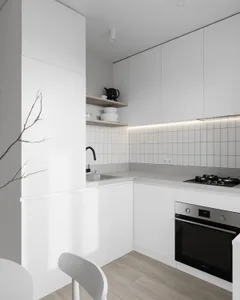 Modern kitchen area with white cabinets, wooden floor, and white tiles on the walls.