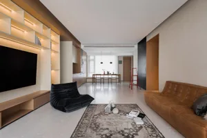 Modern living room with wooden shelves, leather sofa, and carpet