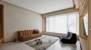 A modern living room featuring a leather sofa, wooden shelves, and a glass window.