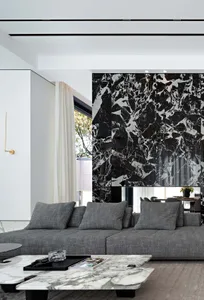 A modern living room with a white marble wall, a grey sofa, and a marble coffee table.