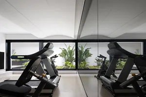 Minimalist fitness center with metal treadmills and glass walls.
