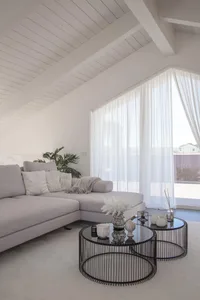 A spacious, minimalist living room featuring a large sectional sofa adorned with white cushions, positioned in front of a lar