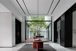 A minimalist living room with a metal table centerpiece, surrounded by white walls and black accents, featuring greenery outs
