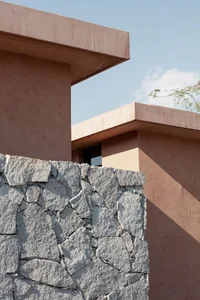 A minimalist building with a stone exterior against a clear blue sky.