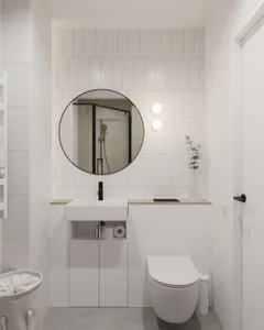 A minimalist bathroom featuring white tiles, a sink, a mirror, and a toilet.