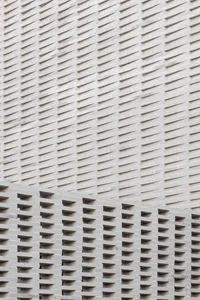 A detailed view of modern architecture featuring a repetitive, geometric pattern made of concrete bricks.