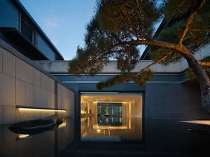 A minimalist residential home featuring concrete and glass materials at dusk.