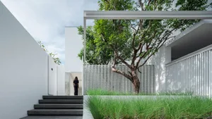 A modern house with a concrete exterior and a tree in the foreground.