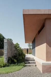 Concrete exterior of a modern building with plants and a pathway.