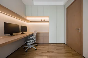A modern home office featuring a desk with two monitors, a chair, and black storage units.