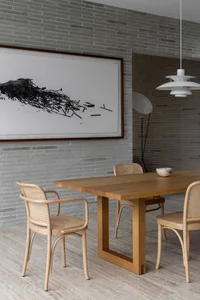 Modern interior design featuring a wooden dining table with rattan chairs and a minimalist white pendant light.