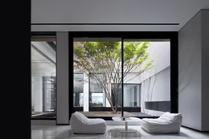 A minimalist modern living room with glass windows and white furniture.