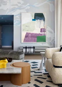 A modern living room with mixed materials, featuring contemporary furniture, a large abstract painting, and a geometric rug.