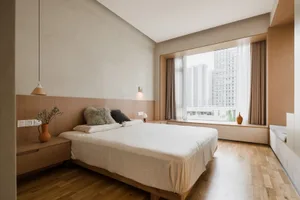 A modern minimalist bedroom featuring wooden furnishings and a large window overlooking a cityscape.