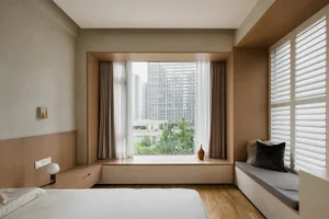 Minimalist bedroom with large windows, wooden walls, and a white bed.