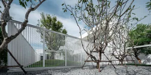 Modern residential design featuring metal fencing, concrete patio, and gravel ground cover.