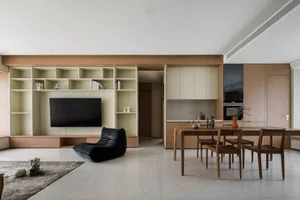 Minimalist living space featuring a modern black lounge chair, dining table with wooden chairs, and a kitchen area with built
