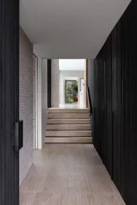 Modern interior featuring wooden staircase with white walls and black accents.