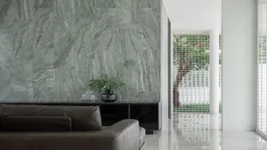 Modern living room with marble walls, white floors, and a brown leather sofa.