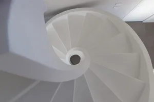 A minimalist white spiral staircase constructed from concrete.