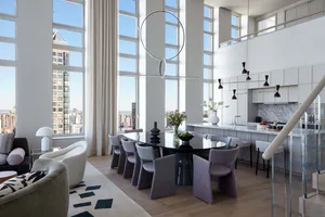 Modern living and dining area with glass table, wooden chairs, marble countertop, and large windows