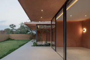 Modern residential exterior with concrete walls and a large glass door.