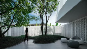 A modern, open-concept residential space featuring concrete floors, glass walls, and lush greenery.