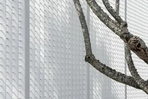 Close-up of modern white-tile architectural exterior with natural tree branch